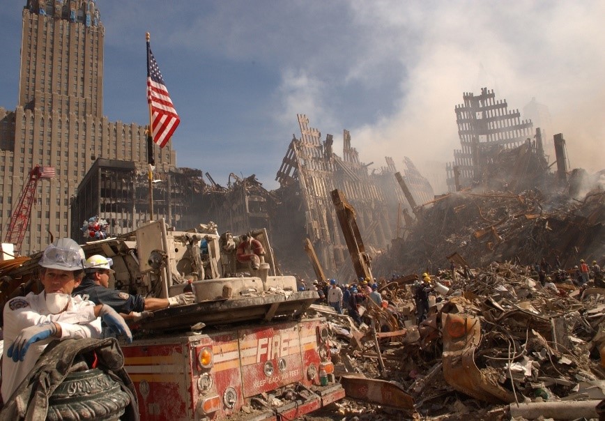 Firetruck with an American flag on it parked in front of Ground Zero debris