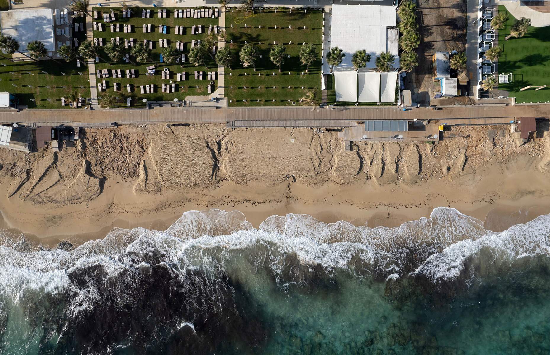 A high angle view of a beach with a walkway and houses along the coast. 