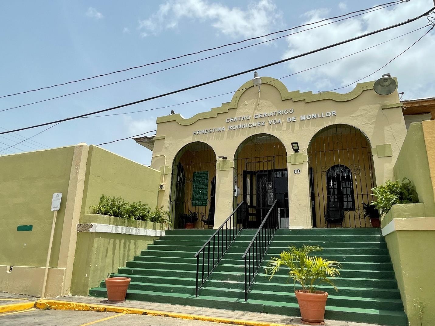 Green and beige building with three arches on front and green stairs.