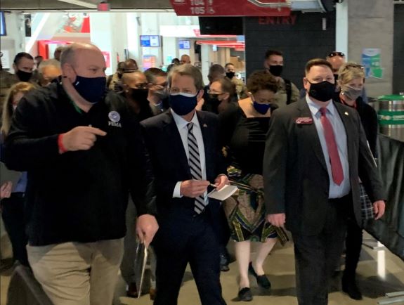 Acting FEMA Administrator, Bob Fenton (left) and Georgia Gov., Brian Kemp (center), engage in conversation as they pass a post-vaccination monitoring area of the community vaccination center at Mercedes-Benz Stadium during a tour of the newly expanded facility.