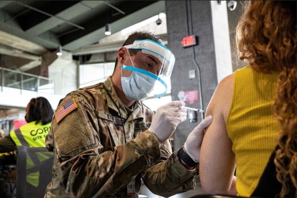 U.S. Army Spc. Joseph Byrd, a combat medic assigned to Fort Stewart, Ga., administers the COVID vaccine to a patient at the Atlanta community vaccination center at Mercedes-Benz Stadium.