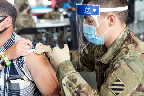 Spc. Ryan Miller administers the COVID vaccine to a patient at the Atlanta community vaccination center at Mercedes- Benz Stadium.