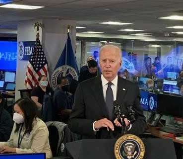 President Joseph R. Biden, Jr. talking in front of a podium with multiple fema staff standing beside and behind him in the nrcc 