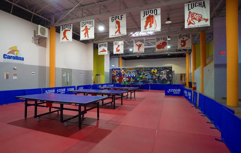 Germán Rieckehoff Sampayo Sports School inside view of room with ping pong tables and orange columns.