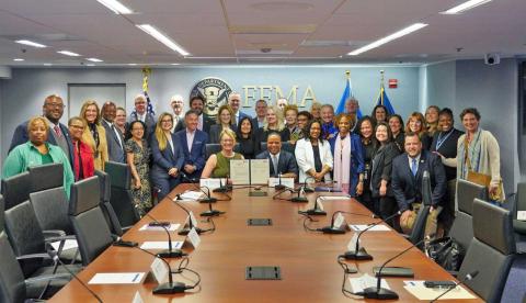 Image with caption: WASHINGTON -- FEMA Administrator Deanne Criswell (left seated) and Founder and CEO of Operation HOPE John Hope Bryant (right seated) along with representatives from FEMA and Operation HOPE and other financial groups following the memorandum of understanding signing. 