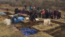 Photo of archaeological dig going on with members of the public watching