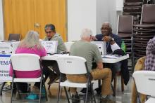 Two FEMA staff members sitting at tables and talking with survivors at the Agriculture Recovery Resource Day event.