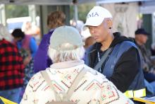 FEMA staff wearing a FEMA hat speaking with a survivor