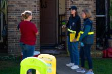 FEMA Disaster Survivor Assistance specialists standing with a resident and her child outside of their home, sharing information about disaster assistance.