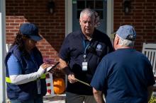 Two FEMA staff members on survivors' front porch, speaking with a resident.