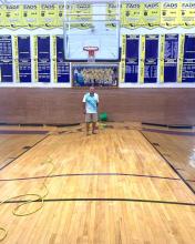 A family member of an Eads High School teacher stands on the school’s gymnasium floor after it drastically buckled and warped within just a few hours on July 27, 2023 in Kiowa County, Colo. The high school gym floor was damaged after a series of severe storms, flooding and tornadoes within a three-week period.