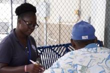 A woman with glasses on looking down a paperwork with an older male in front her