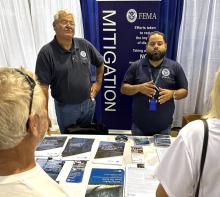 Two men standing in front of a mitigation banner