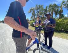 Two women and man with a bike in front of him talking 