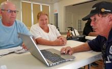 two survivors talk to a FEMA employee across the table