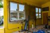 An inside view showing a yellow wall with newly installed windows. 